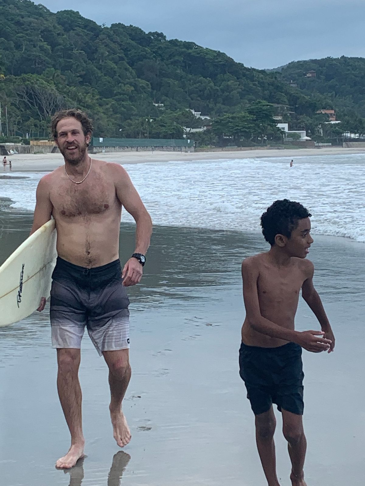 Nick grins as he and the boy come out of the water