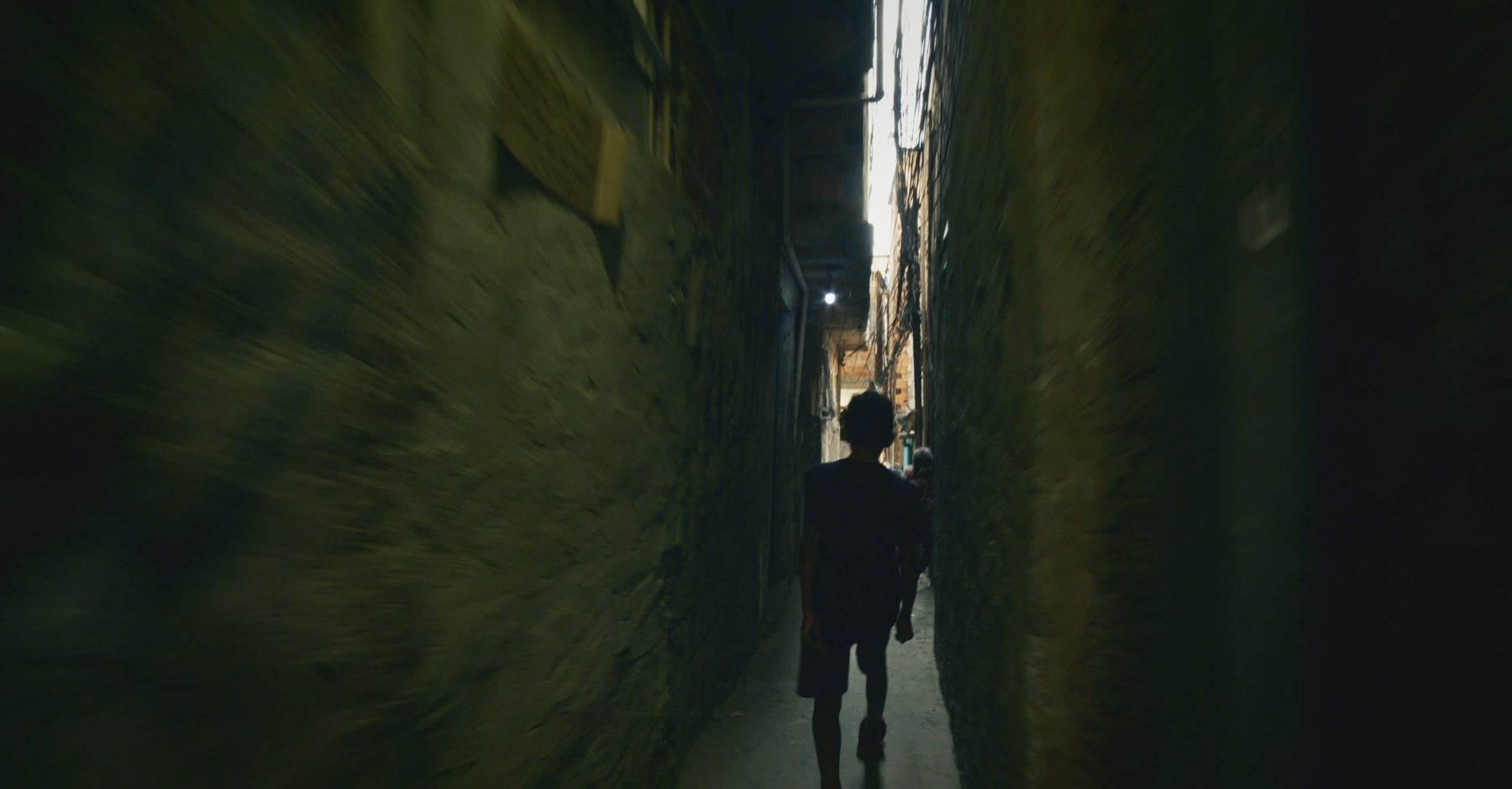 The boy walks a narrow passage between towering walls