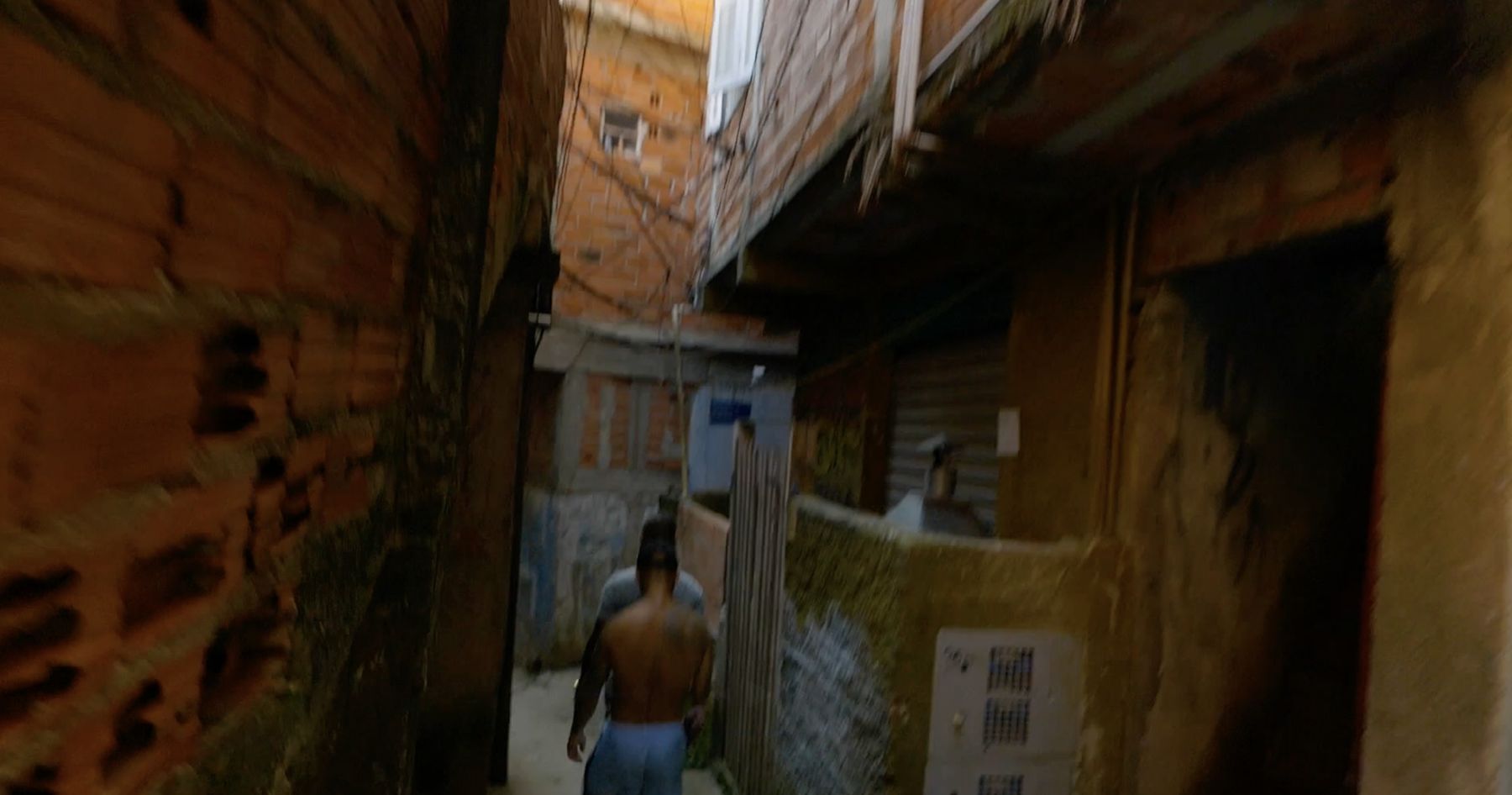 A narrow, shadowed alley between brick houses