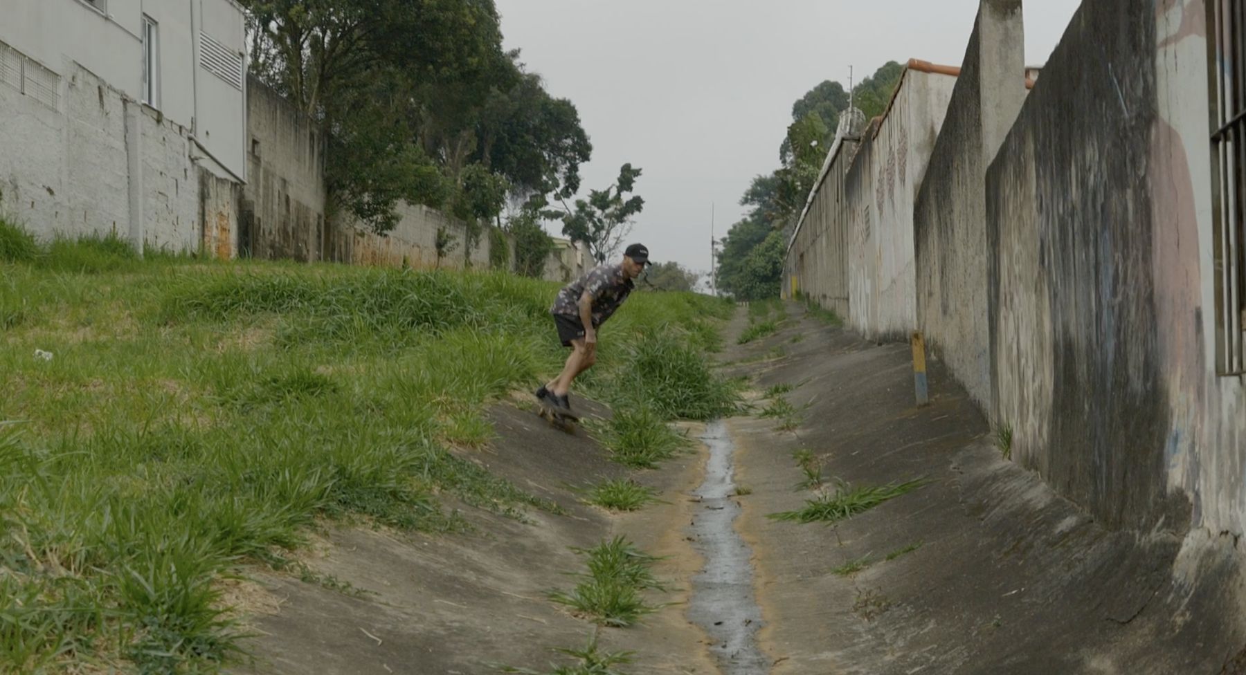 Marcelo drops into a concrete drainage channel on a skateboard