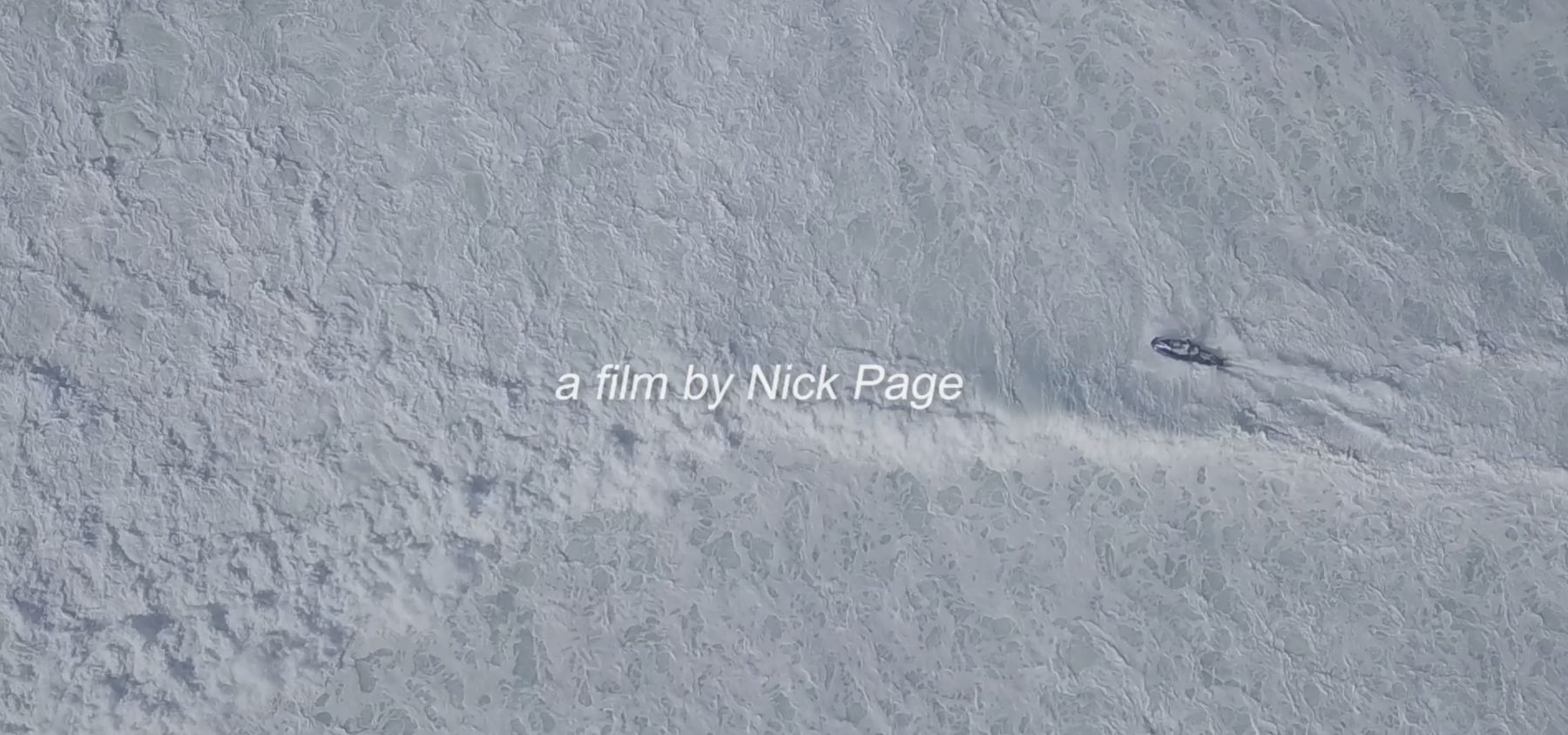 Aerial view of a lone jet ski crossing a vast field of white foam, with the credit a film by Nick Page
