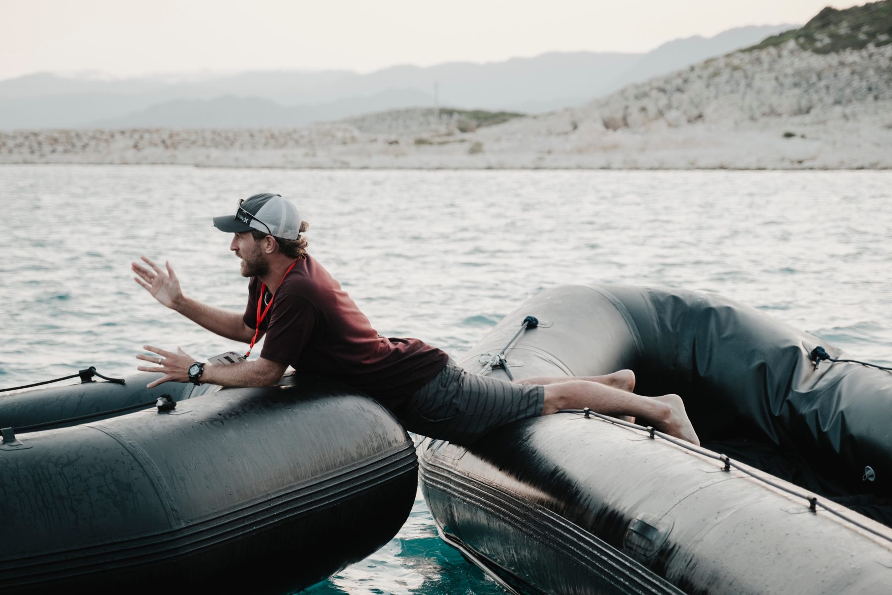 Nick leans across two inflatable boats, directing the action on the water