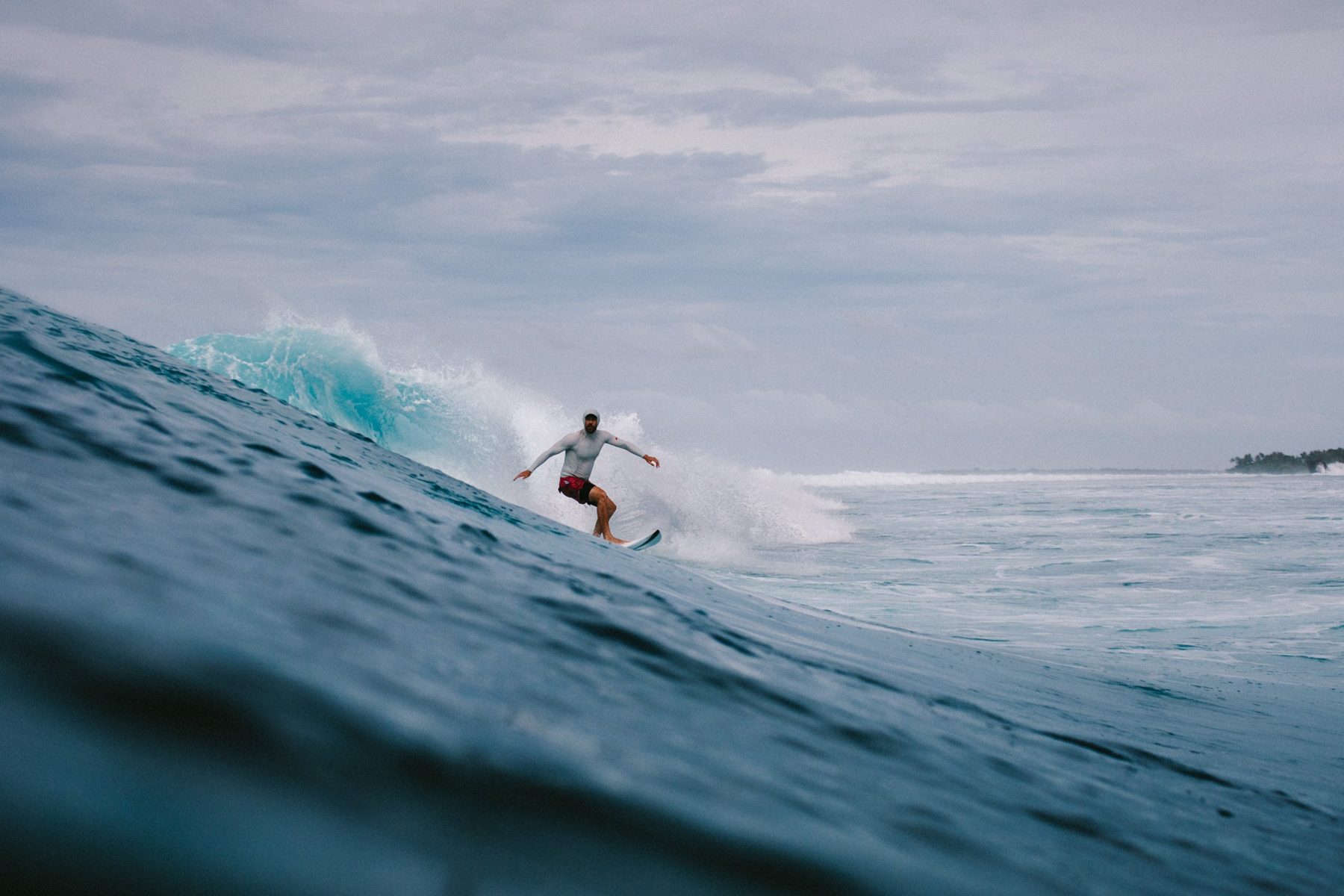 Nick turns off the bottom of a turquoise wave, arms wide