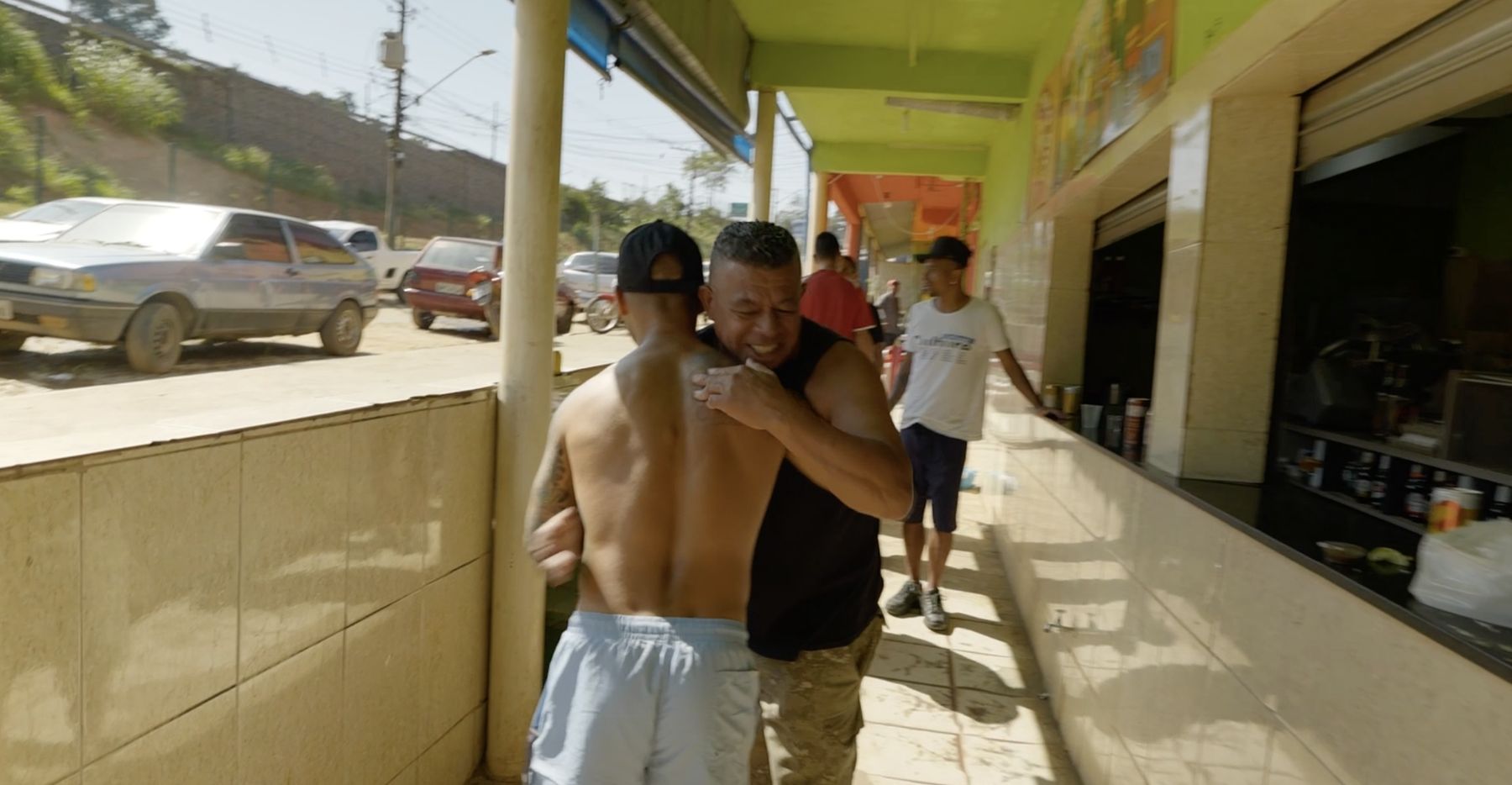 An old friend embraces Marcelo outside the bar