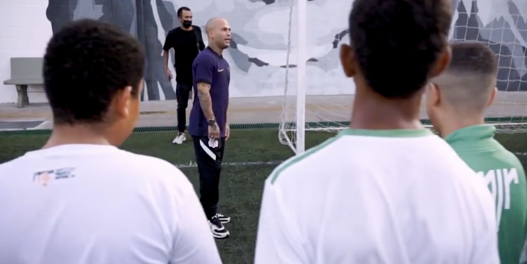 Marcelo talks to a group of young footballers on a pitch