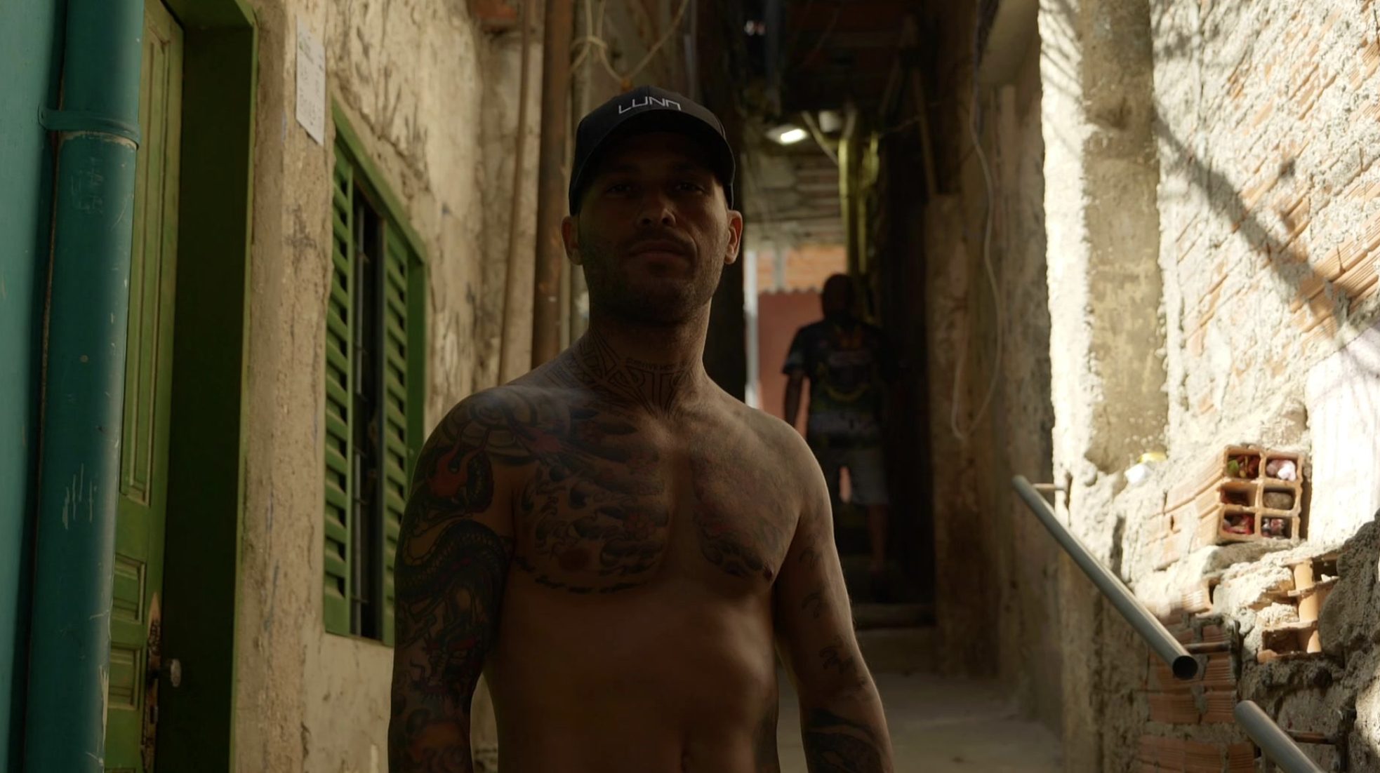 Marcelo Luna in a LUNA cap, standing in a sunlit alley in São Bernardo