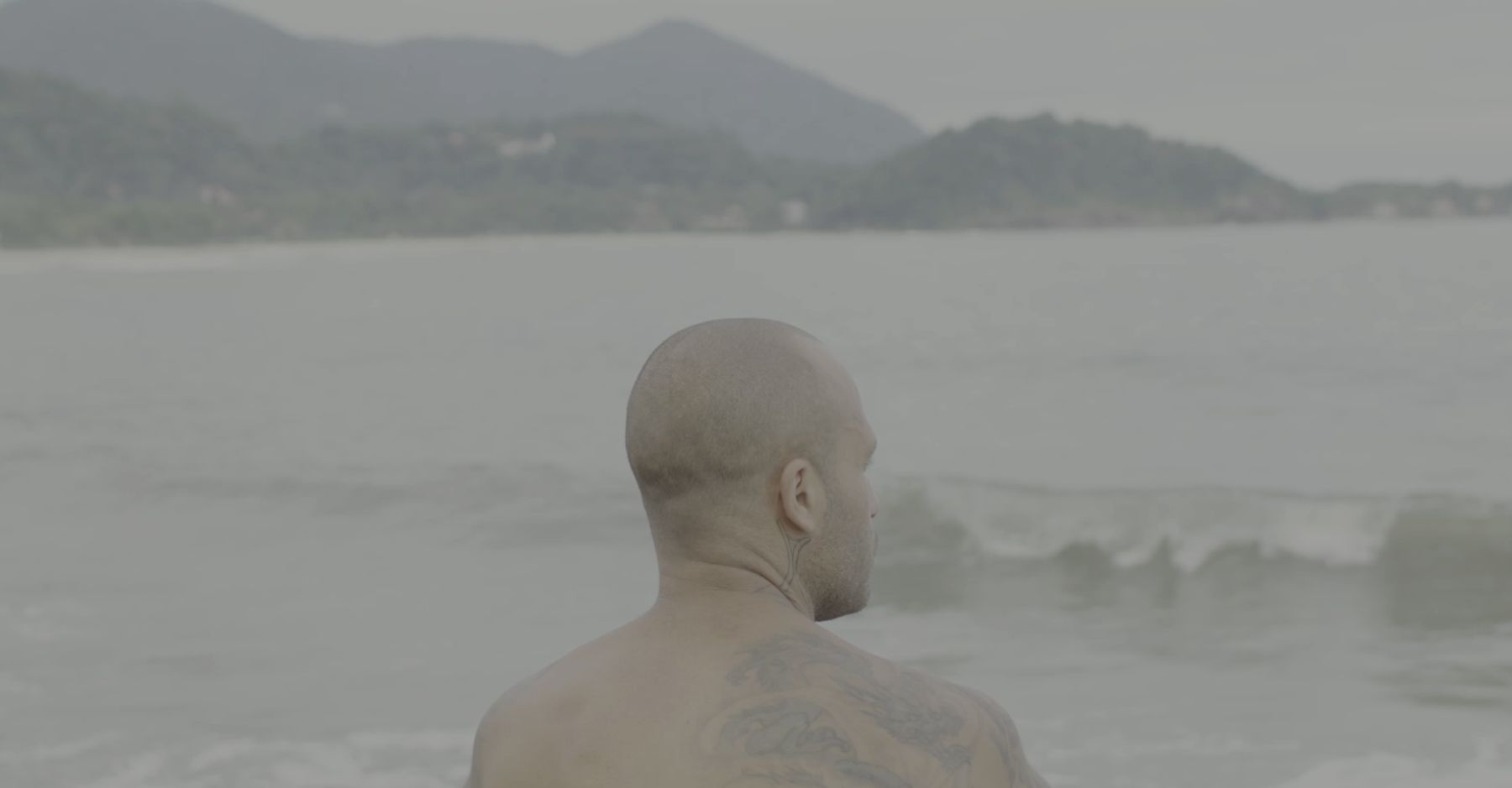 Marcelo, seen from behind, faces a hazy sea and green mountains