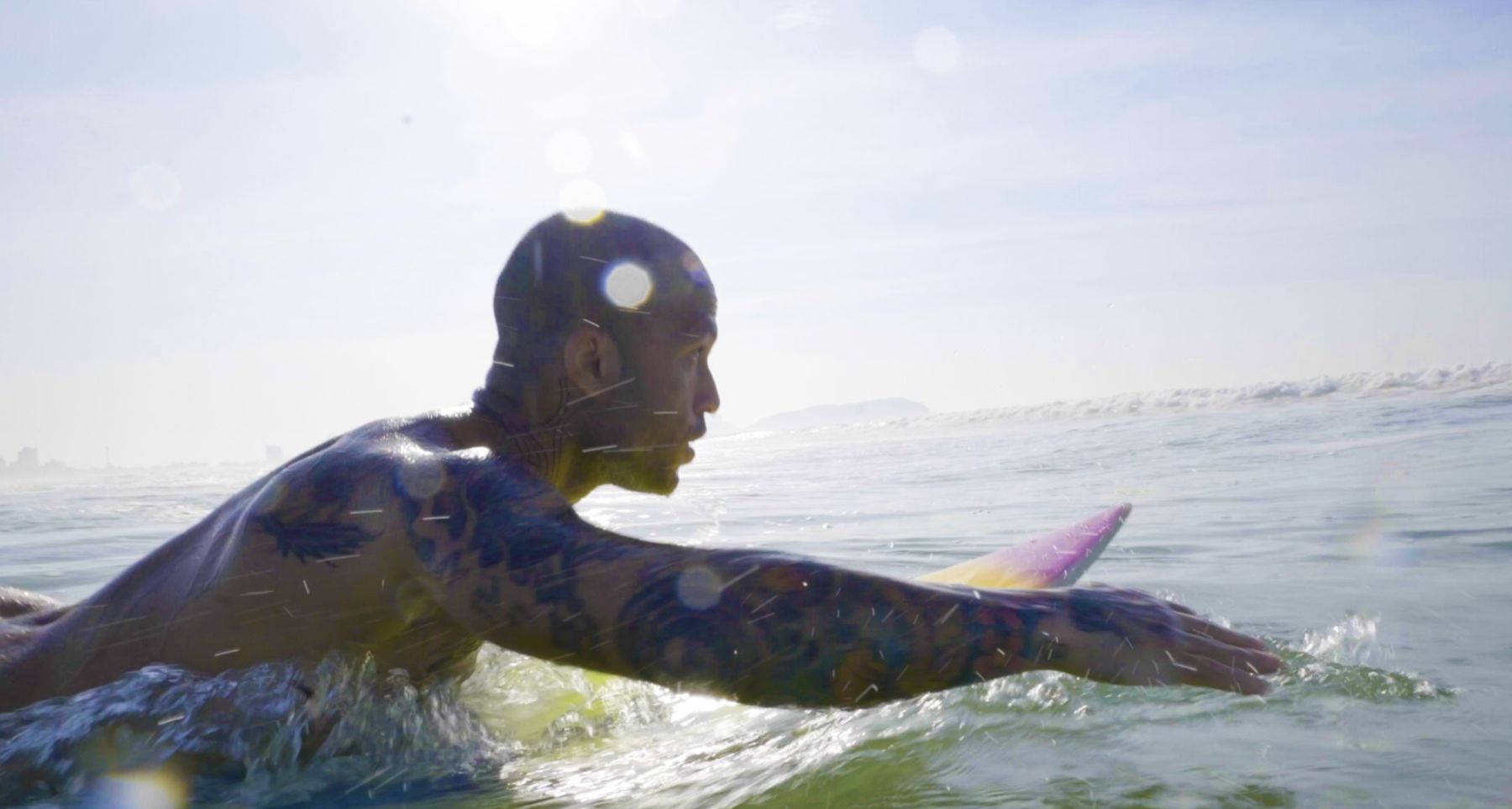 Marcelo paddles out in backlit profile